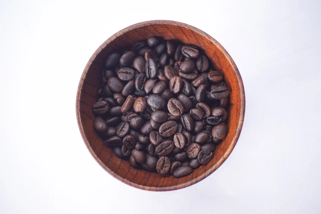 Coffee beans sit in a wooden bowl.