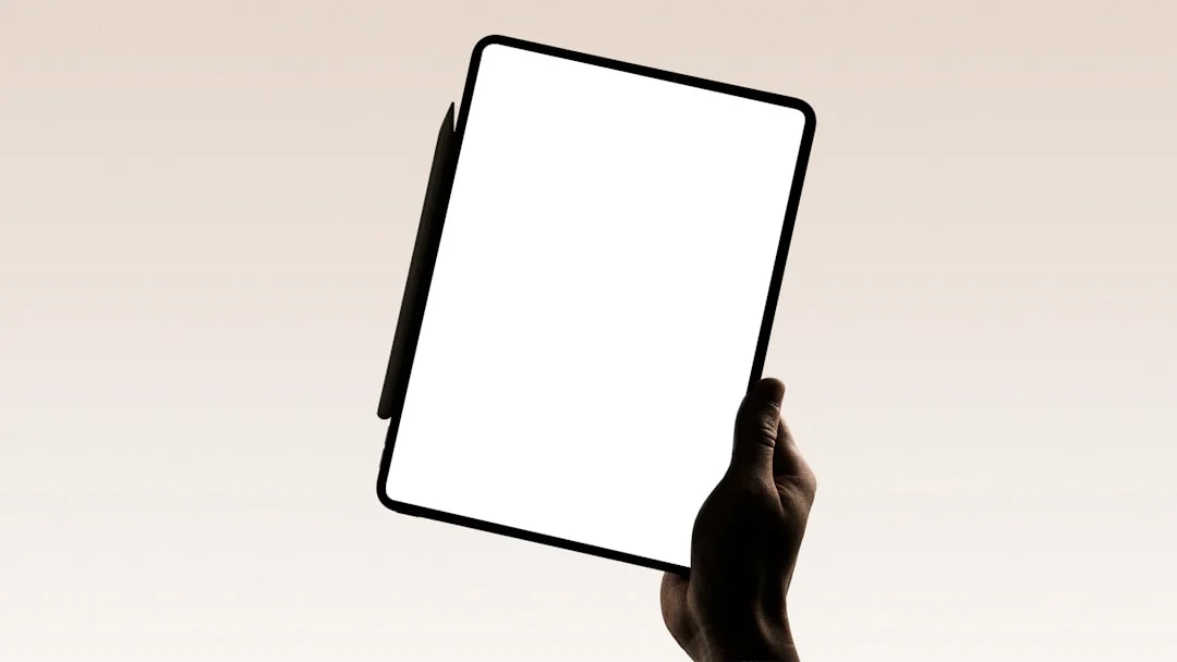 A hand holds a tablet with a blank screen.